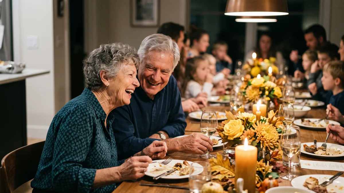 Elderly parents laughing together at a festive anniversary dinner table with autumn flowers, candles and wine